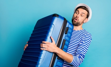 mężczyzna unosi dużą walizkę
