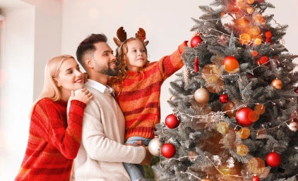 Rodzina wieszająca bombkę na choince świątecznej